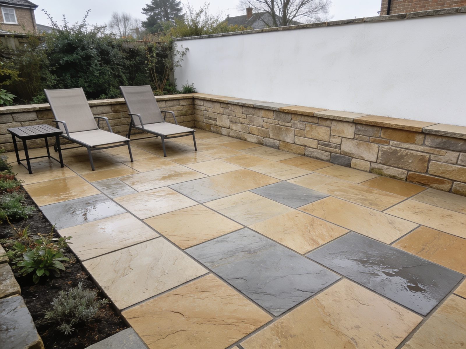 A sandstone patio with large-format paving, a low retaining wall and simple outdoor seating.